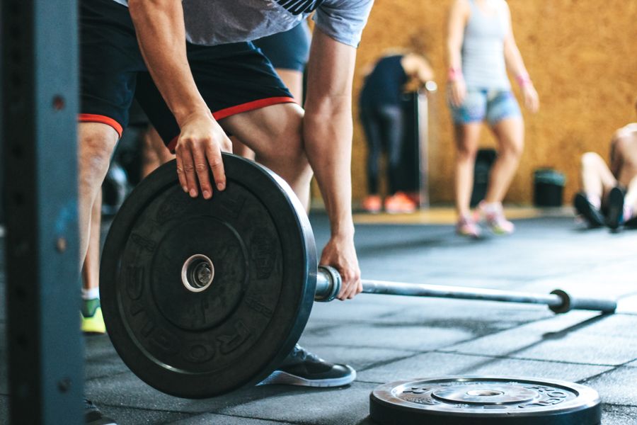 Person in gray shirt holding black dumbbell
